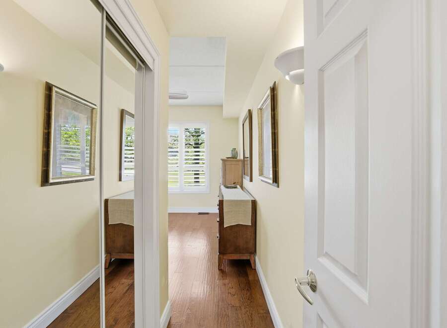 Step into this inviting hallway, featuring a mirrored closet and warm hardwood floors.