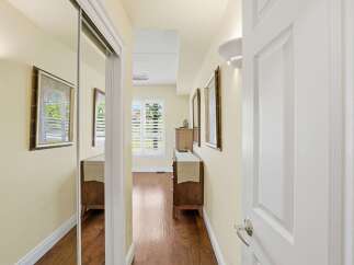 Step into this inviting hallway, featuring a mirrored closet and warm hardwood floors.