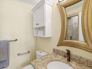 This charming bathroom features a granite-topped vanity with a bronze faucet, complemented by a decorative gold-framed mirror.