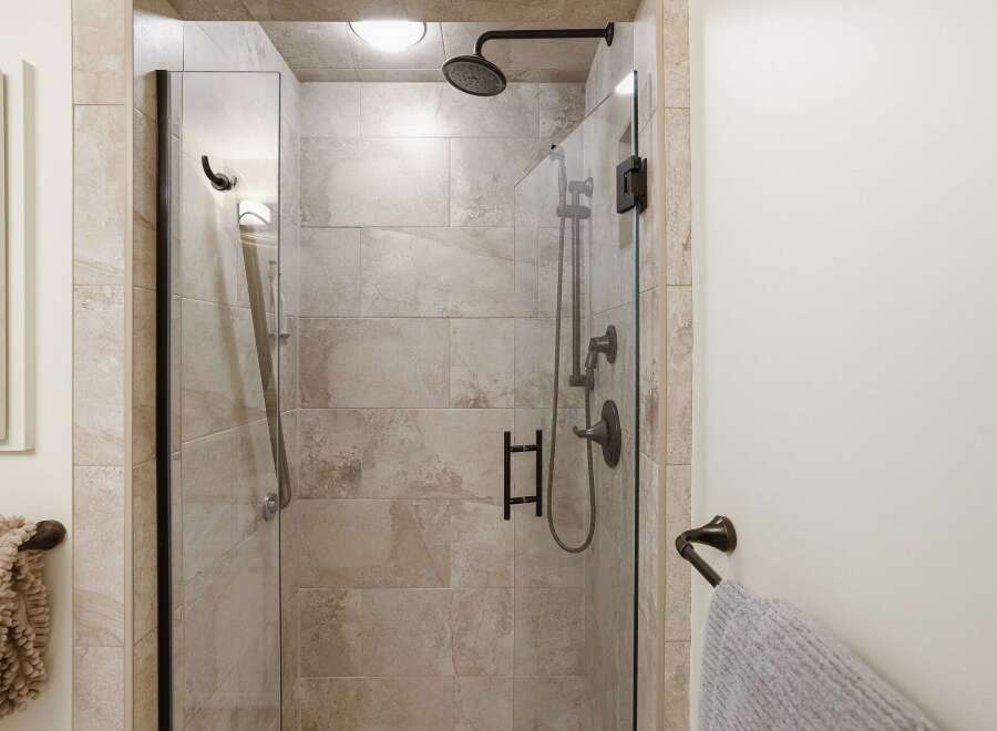 Experience luxury in this modern bathroom featuring a spacious glass-enclosed shower with elegant tilework and dark bronze fixtures.