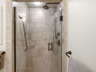 Experience luxury in this modern bathroom featuring a spacious glass-enclosed shower with elegant tilework and dark bronze fixtures.