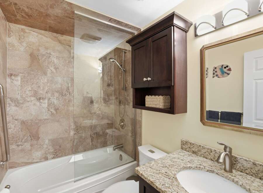 This bathroom features a luxurious tiled shower and tub combination, complemented by a sleek glass enclosure.