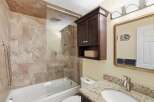 This bathroom features a luxurious tiled shower and tub combination, complemented by a sleek glass enclosure.