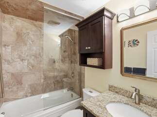 This bathroom features a luxurious tiled shower and tub combination, complemented by a sleek glass enclosure.