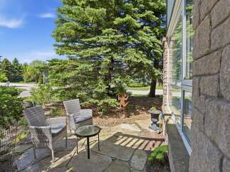 Enjoy your morning coffee on this charming stone patio, complete with comfortable wicker seating and a glass-top table.