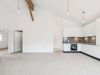 Discover this modern and spacious open-plan living area featuring a sleek, white kitchen with integrated appliances and ample cabinet space.
