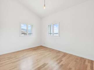 Discover this bright and airy room featuring pristine white walls and a beautiful light wood floor.