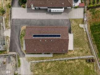 Discover this unique property featuring a modern building with a distinctive skylight on its tiled roof, complemented by adjacent greenhouses.