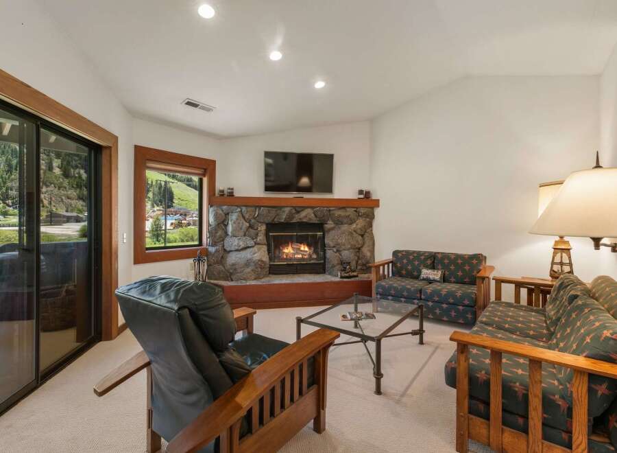 Cozy up by the stone fireplace in this inviting living room, perfect for relaxing after a day of outdoor adventures.