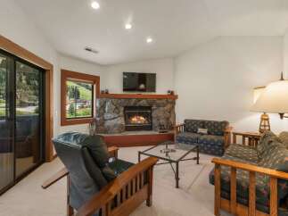 Cozy up by the stone fireplace in this inviting living room, perfect for relaxing after a day of outdoor adventures.