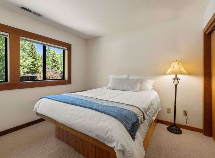 This cozy bedroom features a comfortable queen-size bed adorned with crisp white linens and a stylish blue throw blanket.
