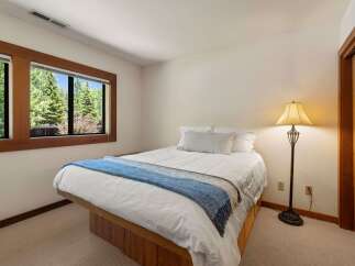 This cozy bedroom features a comfortable queen-size bed adorned with crisp white linens and a stylish blue throw blanket.
