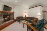 Cozy up by the stone fireplace in this inviting living room, featuring comfortable seating and a large flat-screen TV for entertainment.