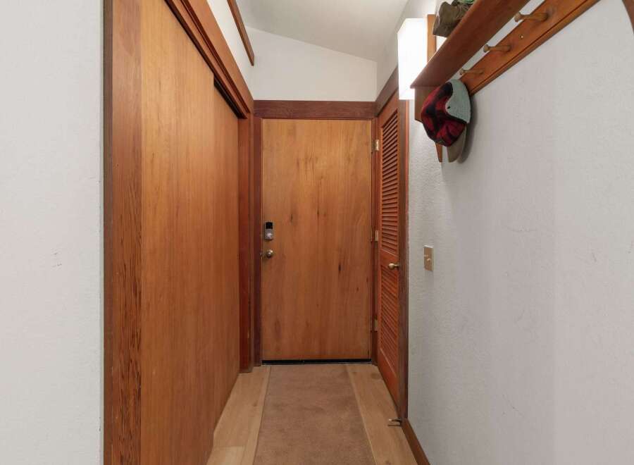 Step into this charming entryway featuring warm wooden doors and a convenient coat rack with shelving.