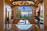 Experience breathtaking lake views from this stunning kitchen, featuring a large arched window framing the serene waters and surrounding mountains.