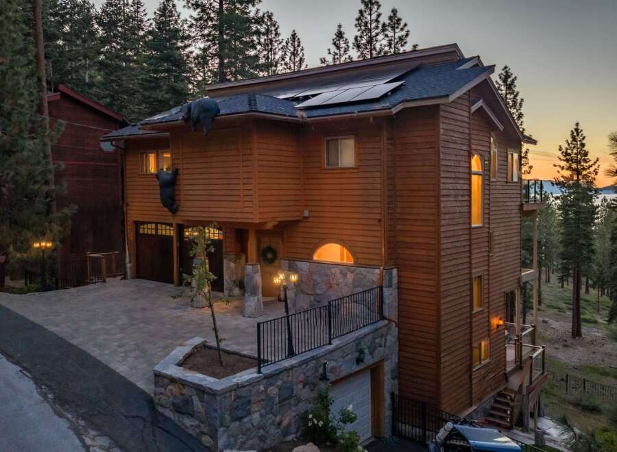 Experience luxury mountain living in this stunning wood-sided home, featuring a unique bear-themed exterior decoration.