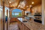 Experience luxury living in this stunning kitchen featuring a large granite island with a sink and a breathtaking arched window offering panoramic lake and mountain views.