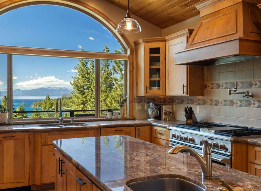 Experience breathtaking lake and mountain views from this stunning kitchen, featuring a large arched window that floods the space with natural light.