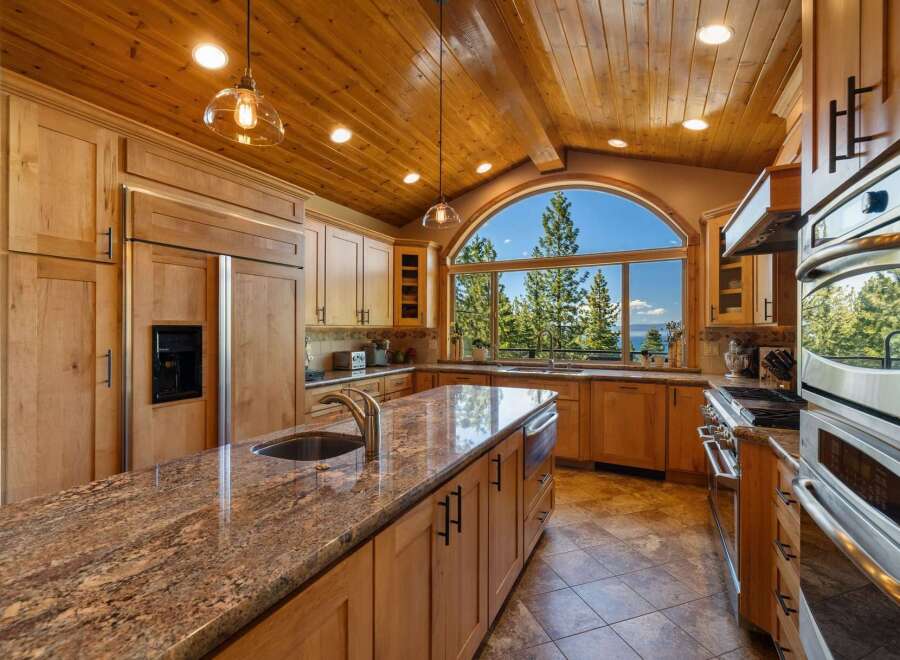 Experience breathtaking views from this stunning kitchen, featuring custom wood cabinetry and a large granite island with a double sink.