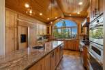Experience breathtaking views from this stunning kitchen, featuring custom wood cabinetry and a large granite island with a double sink.