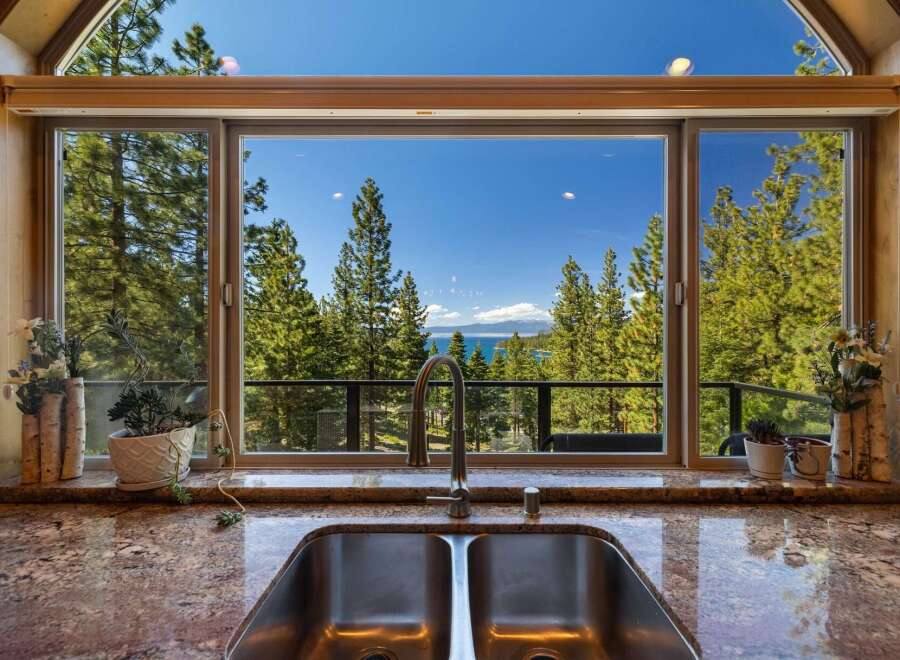 Experience breathtaking lake and mountain views from this stunning kitchen, featuring a large double sink and a modern faucet.