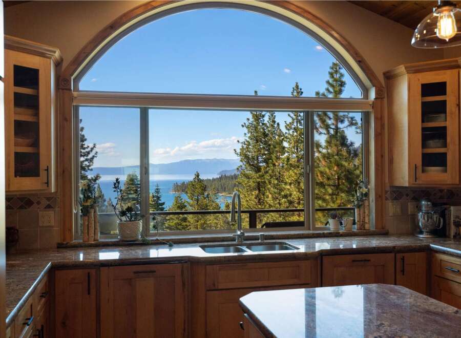 Experience breathtaking lake and mountain views from this stunning kitchen, featuring a large arched window that floods the space with natural light.