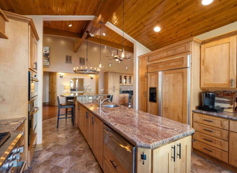 Experience luxury living in this stunning kitchen, featuring custom wood cabinetry and a large granite island with a built-in sink.