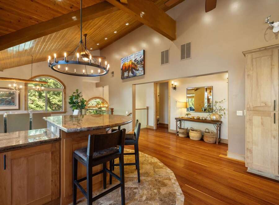 Experience rustic elegance in this spacious home featuring a grand circular chandelier and exposed wooden beams.