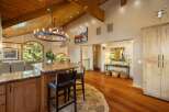 Experience rustic elegance in this spacious home featuring a grand circular chandelier and exposed wooden beams.