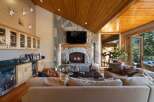 Experience luxury mountain living in this stunning great room, featuring a grand stone fireplace and a vaulted wood-paneled ceiling.