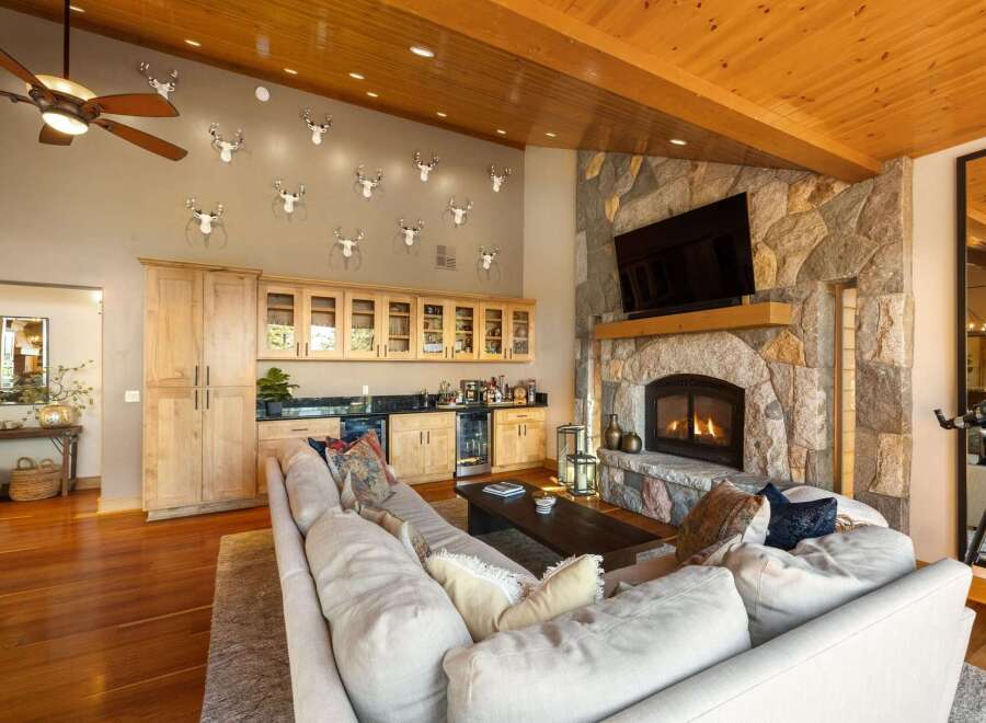 Experience rustic luxury in this stunning living room, featuring a grand stone fireplace and a fully equipped wet bar perfect for entertaining.