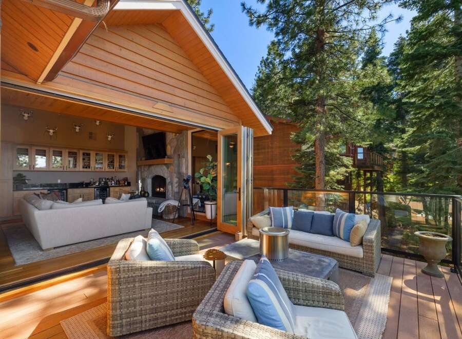 Experience seamless indoor-outdoor living with this stunning property, featuring a spacious deck perfect for entertaining and a cozy interior with a stone fireplace and a well-appointed bar area.