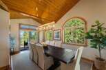 Experience breathtaking views from this stunning dining room, featuring a rustic antler chandelier and a large wooden table perfect for gatherings.