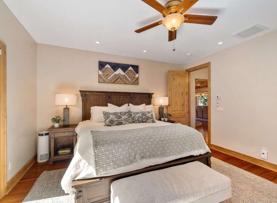 Experience ultimate comfort in this luxurious master bedroom, featuring a grand wooden bed frame and plush bedding.