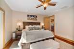 Experience ultimate comfort in this luxurious master bedroom, featuring a grand wooden bed frame and plush bedding.