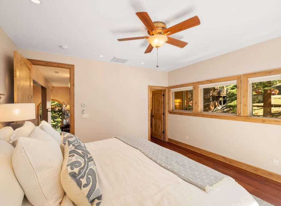 Experience serene living in this charming bedroom, featuring a plush bed adorned with decorative pillows and a cozy throw.