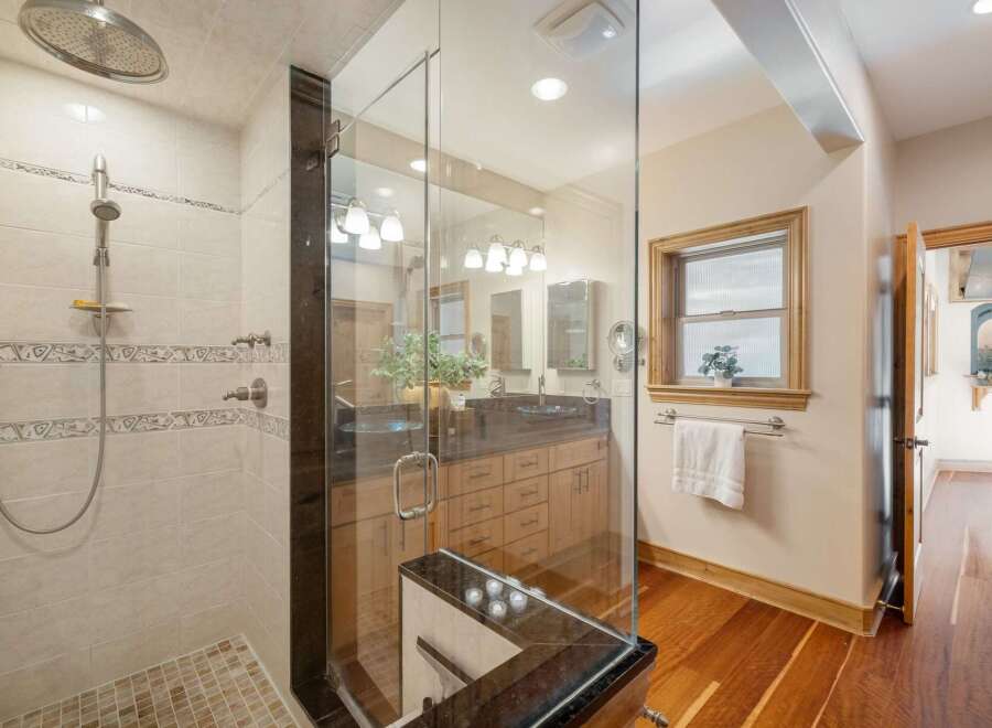 Experience luxury in this stunning bathroom featuring a spacious glass-enclosed shower with a rainfall showerhead and elegant tile work.