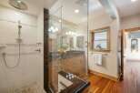 Experience luxury in this stunning bathroom featuring a spacious glass-enclosed shower with a rainfall showerhead and elegant tile work.