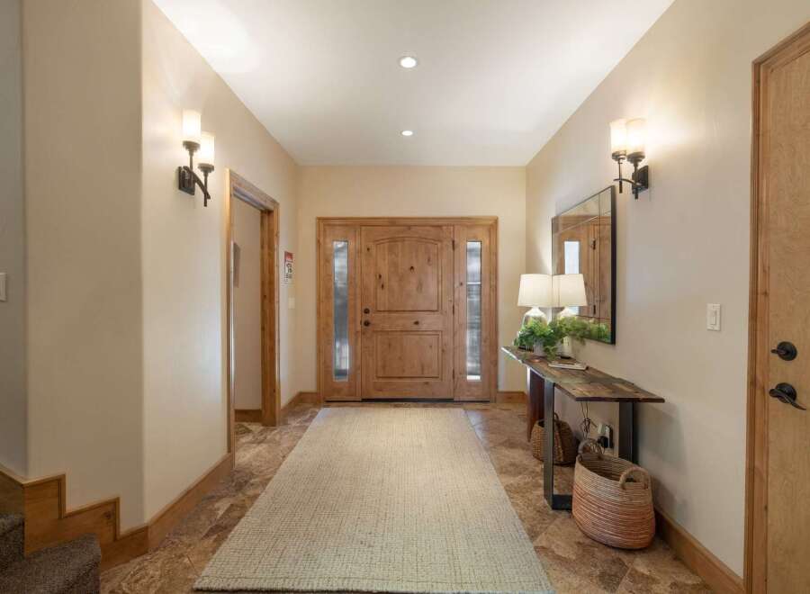 Step into this inviting entryway featuring a beautiful wooden double door and a long, neutral-toned rug that guides you further into the home.