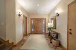 Step into this inviting entryway featuring a beautiful wooden double door and a long, neutral-toned rug that guides you further into the home.