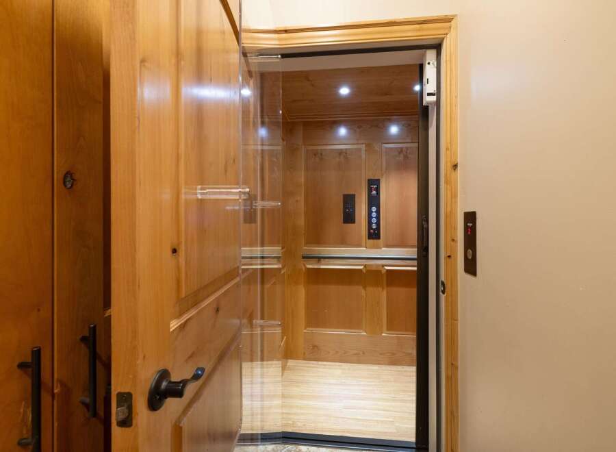 Experience seamless living with this elegant home elevator, featuring a luxurious wood-paneled interior and a sleek glass enclosure.