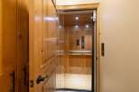 Experience seamless living with this elegant home elevator, featuring a luxurious wood-paneled interior and a sleek glass enclosure.