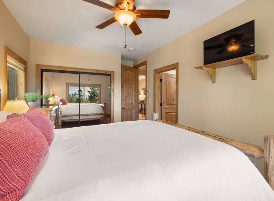 Experience rustic charm in this cozy bedroom featuring a comfortable bed with plush pink pillows and a natural wood headboard.