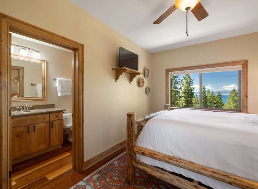 Experience breathtaking lake and mountain views from this charming bedroom, complete with a rustic log bed and a private ensuite bathroom.