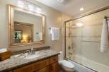 This charming bathroom features a spacious vanity with a granite countertop and a wooden cabinet, complemented by a large wooden-framed mirror.