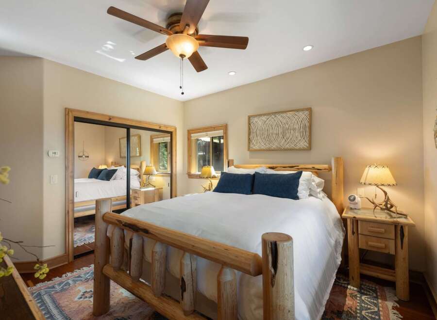 Experience rustic charm in this inviting bedroom, featuring a cozy log bed and plush blue accent pillows.