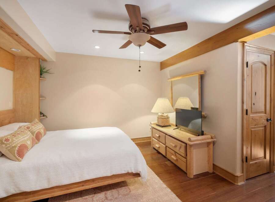 This charming bedroom features a cozy queen-size bed with a white textured comforter and decorative pillows.