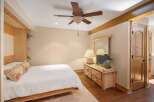 This charming bedroom features a cozy queen-size bed with a white textured comforter and decorative pillows.