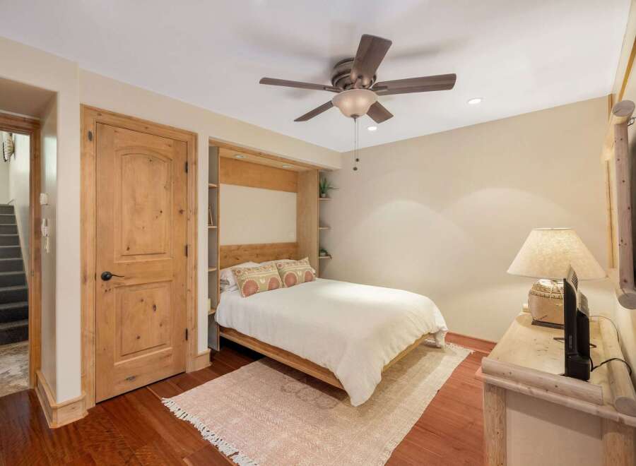 This charming bedroom features a comfortable queen-size bed with a white duvet, complemented by decorative pillows.
