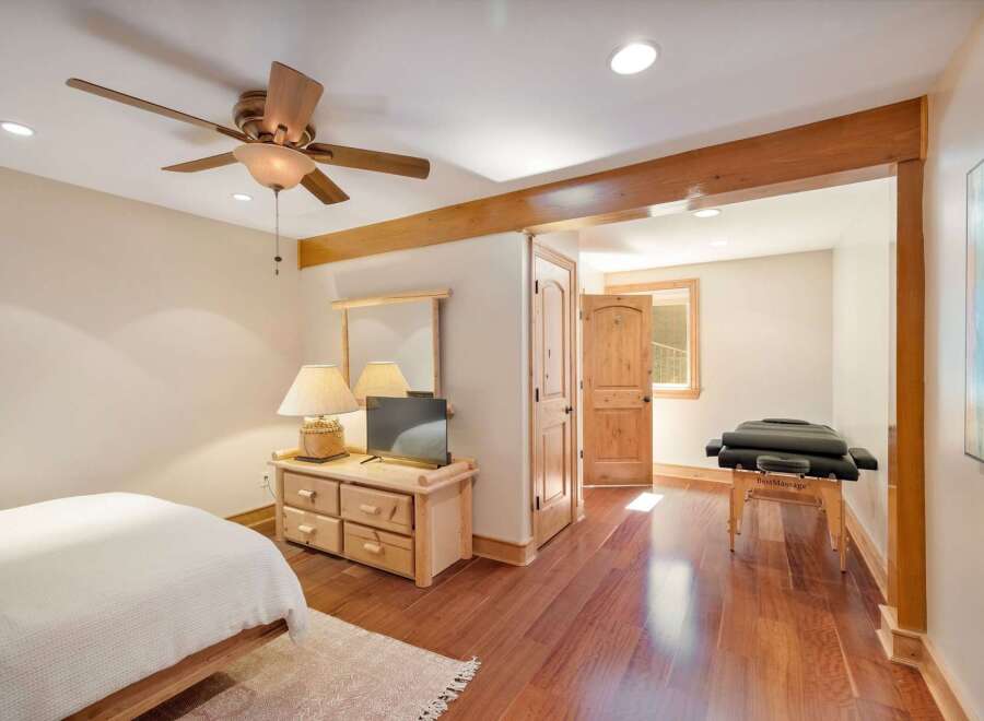 Experience ultimate relaxation in this serene bedroom featuring a comfortable bed and a dedicated massage area.